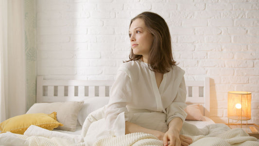Woman relaxing in a softly lit bedroom — beginner's guide to using a g-spot vibrator